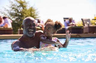 Senior playing with their grandchild in a local swimming pool